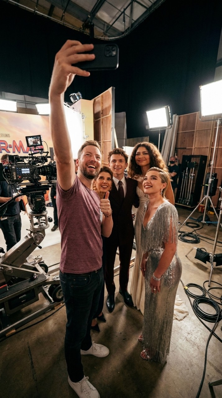 KI-generiertes Selfie: die Person aus Bild 1 steht mit den Schauspielern aus Bild 2 an einem Filmset